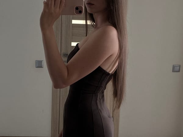 Mirror selfie in a strapless dress, pink phone in hand