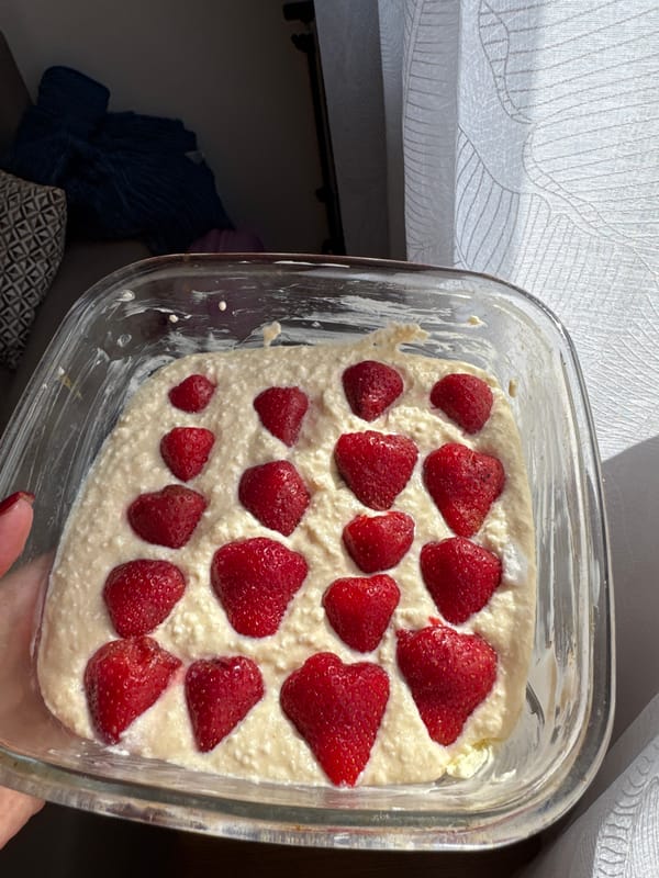 Person prepares strawberry dessert in glass baking dish