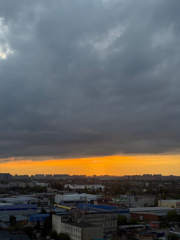 Dramatic storm clouds contrast golden light over Krasnodar cityscape