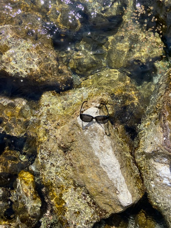 Woman in white dress photographed at rocky waterside in Montenegro