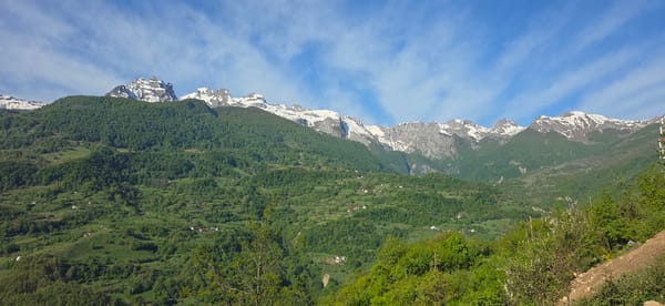 Snow-capped peaks filmed above green forests in Montenegro morning