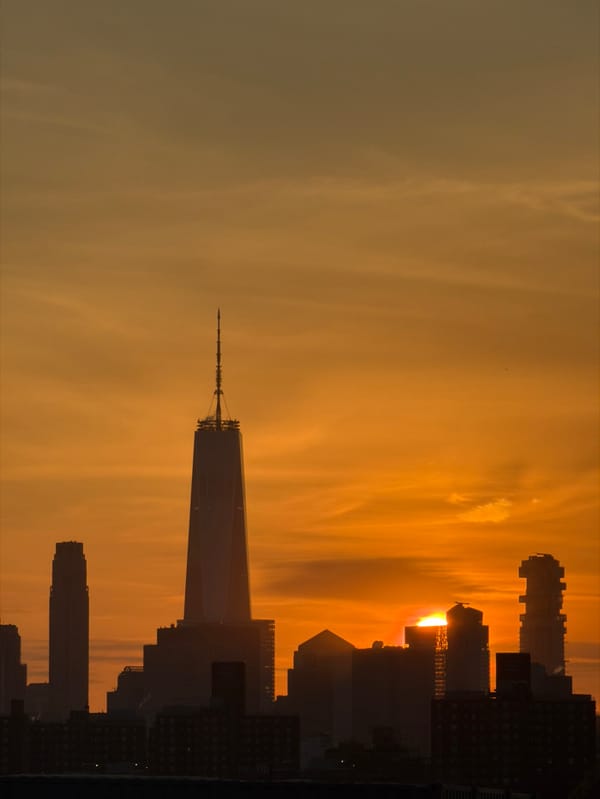 Golden sunset silhouettes NYC skyline featuring One World Trade Center