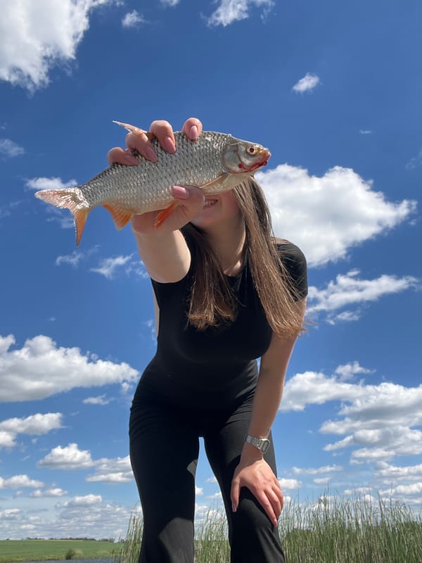 Person displays fish catch under blue skies in Rudky