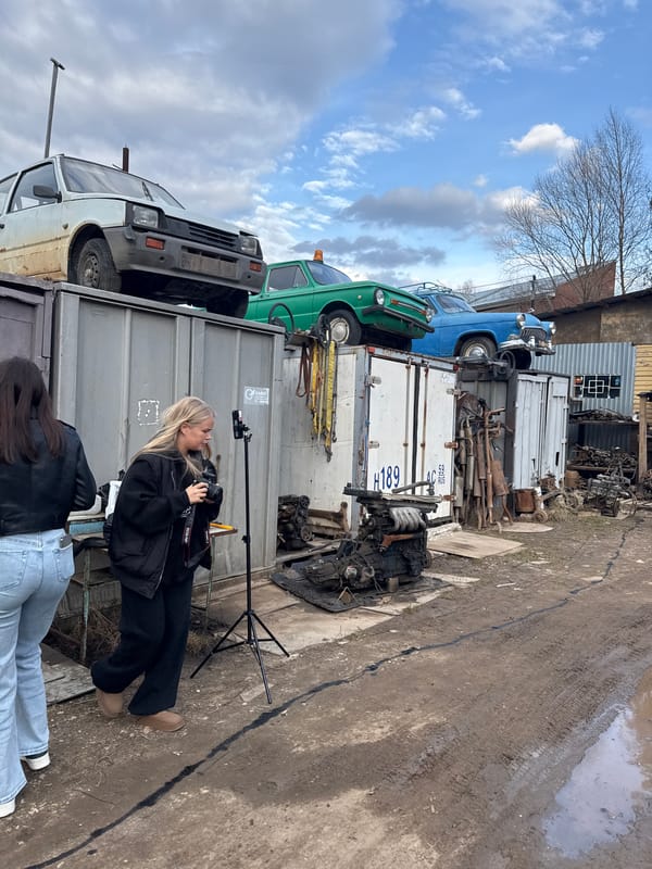 Young women film smartphone video at Russian auto junkyard