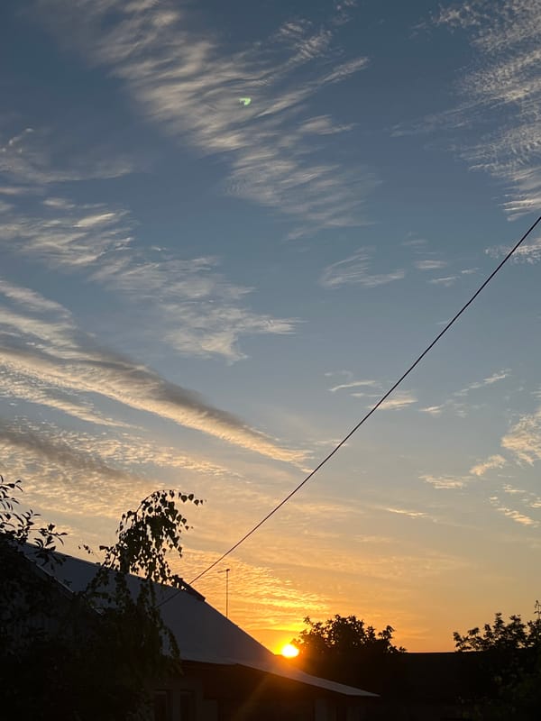 Slobozia sunset: blue sky, wispy clouds, and rooftop silhouettes