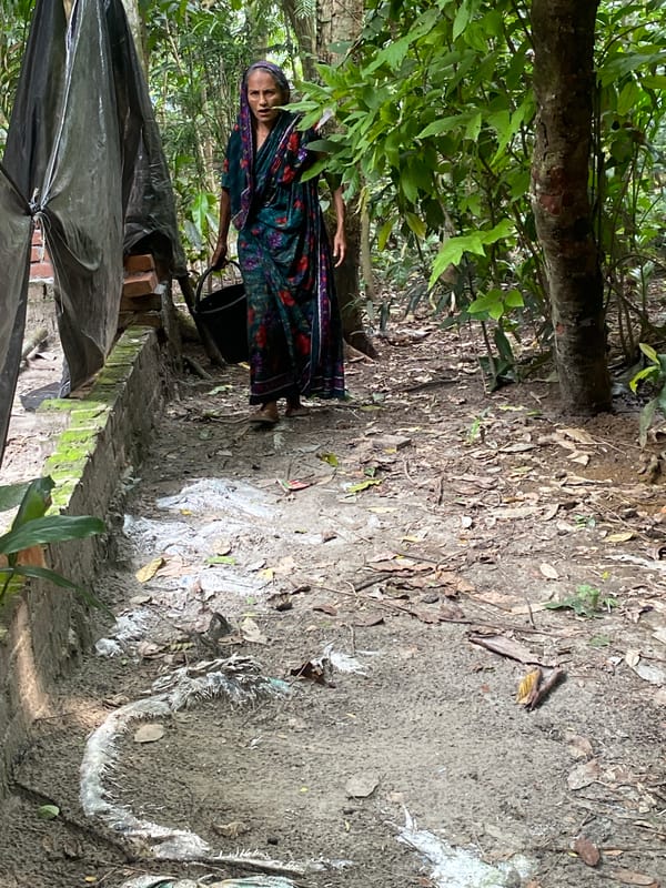 Woman in headscarf stands near brick structure in Bangladesh