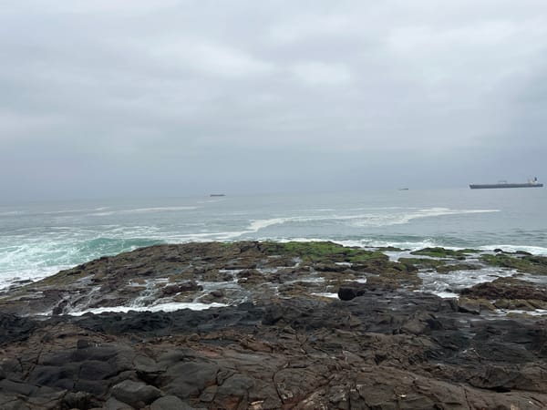Surfers work choppy waves off Arica's rocky Pacific shore.
