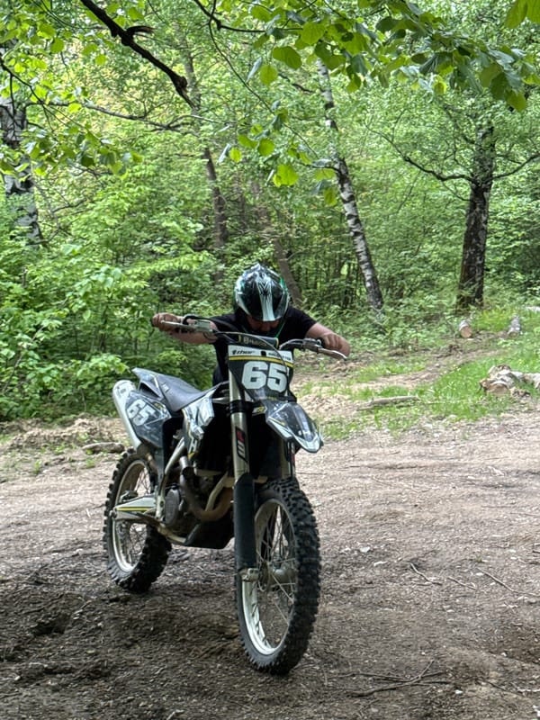 Motorcyclist rides through forest near Berkovitsa welcome sign