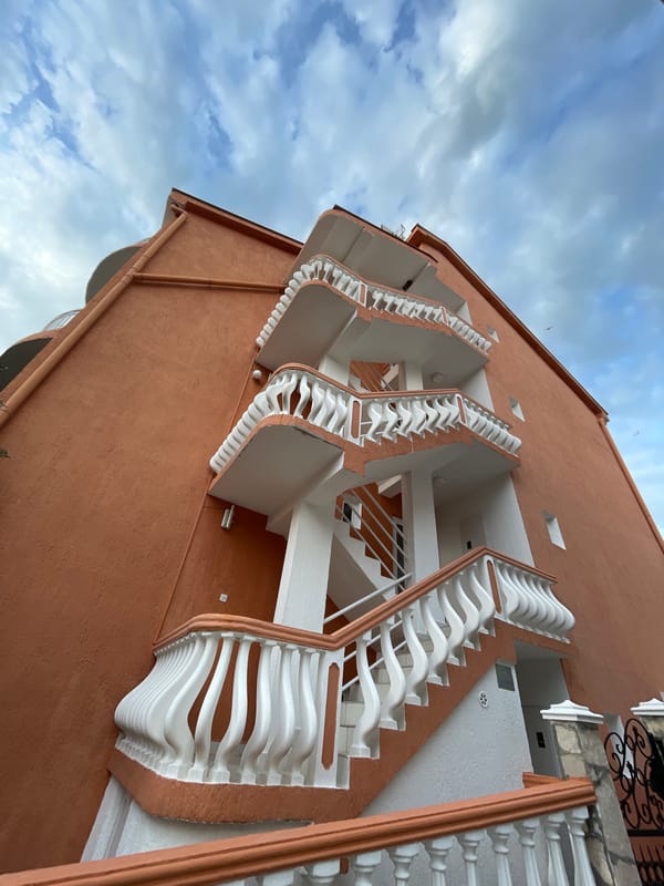 Orange building with white balconies photographed in Rafailovići