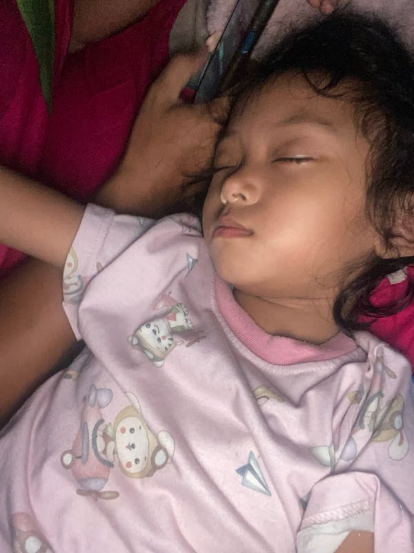 Child sleeps peacefully in pink cartoon top, Gelam