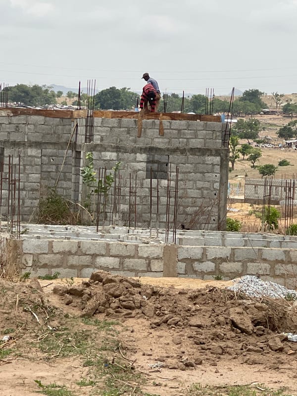 Construction workers build concrete block structures in Angwan Sayawa