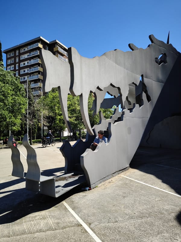 Man sits inside gray sculpture in Barcelona public space