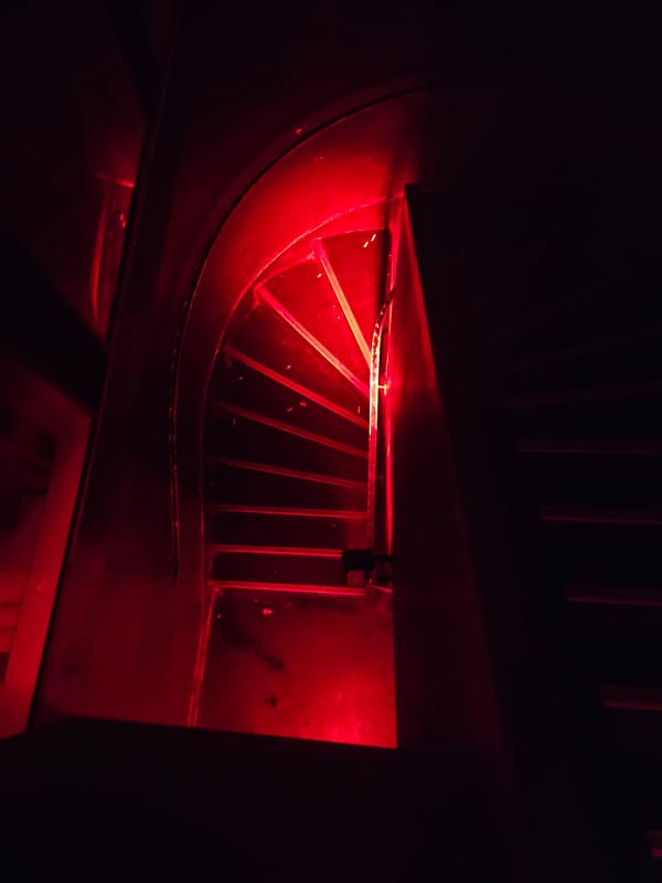 Red-lit machinery grate observed at unknown location