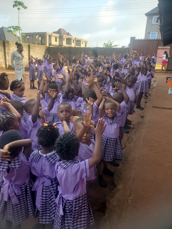 Children in purple uniforms raise arms outdoors in Nigeria