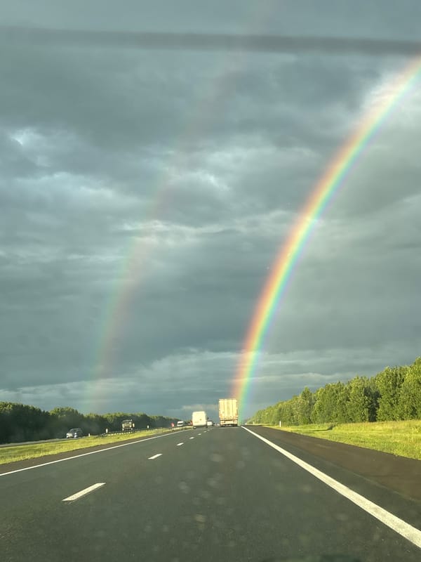 Double rainbow over a Russian highway, shot from a moving car