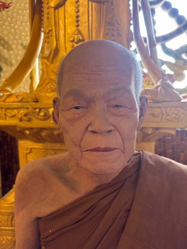 Hyperrealistic monk statues and golden deity shrine in Vietnamese temple