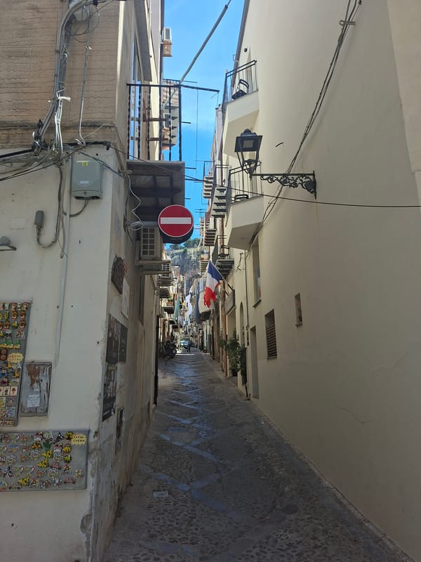 Narrow alleyway with white buildings documented in Cefalù, Italy