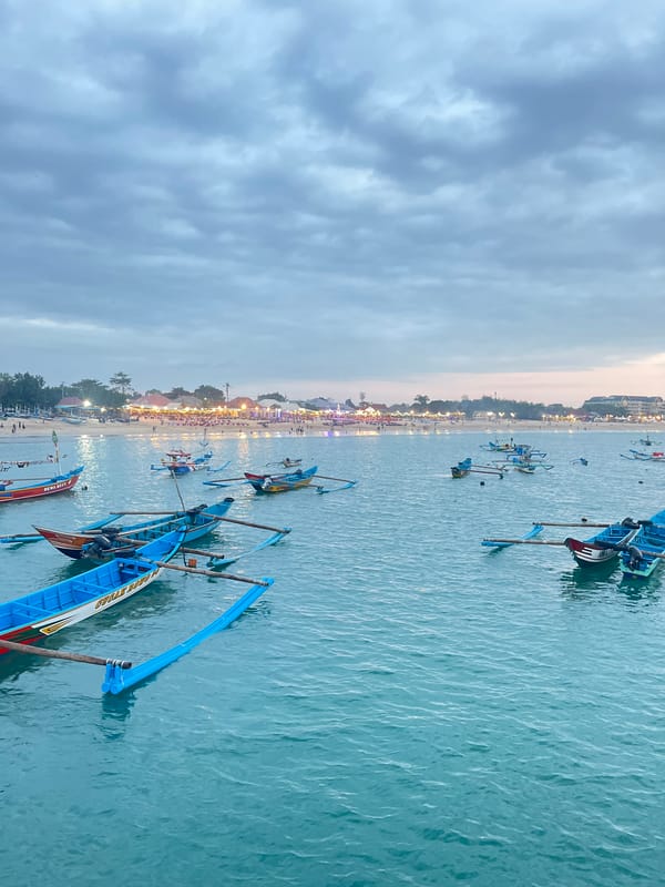 Kuta Beach at dawn — fishing boats, overcast skies, quiet waterfront