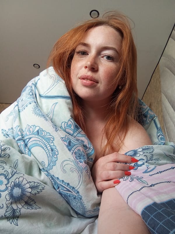 Red-haired woman rests in bed in Yurgamysh, Russia