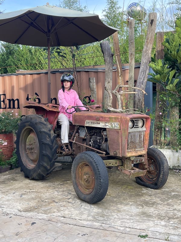 Person operates vintage tractor in rural Vietnam village