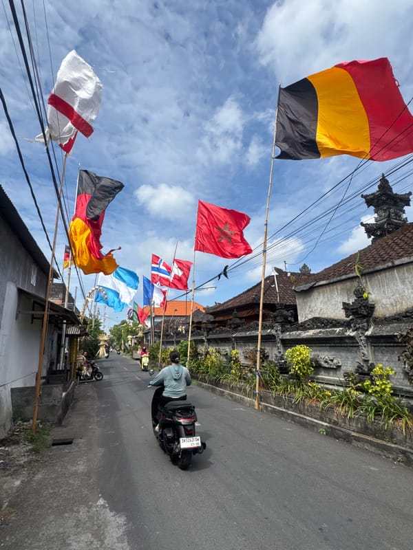 Rows of international flags line a Kuta street on a cloudy day