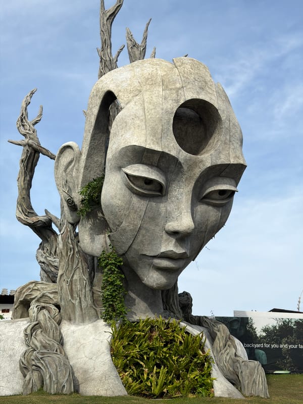 Monumental stone head sculptures merging with roots and greenery in Bali