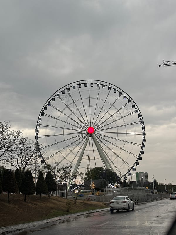 Rainy night drive past illuminated Ferris wheel in Puebla