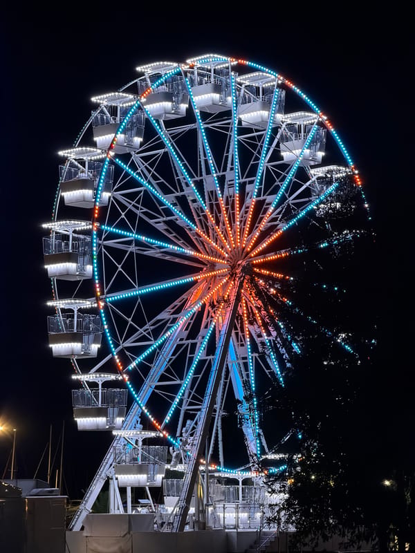 Ferris wheel lights up Budva's summer night alongside a gelato shop