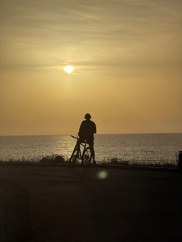 Cyclist silhouetted against sunset along Mediterranean coast in Bat Yam
