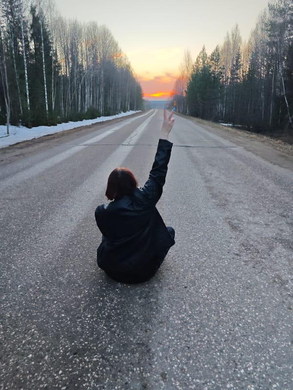 Person sits on road during sunset in Markovo, Russia