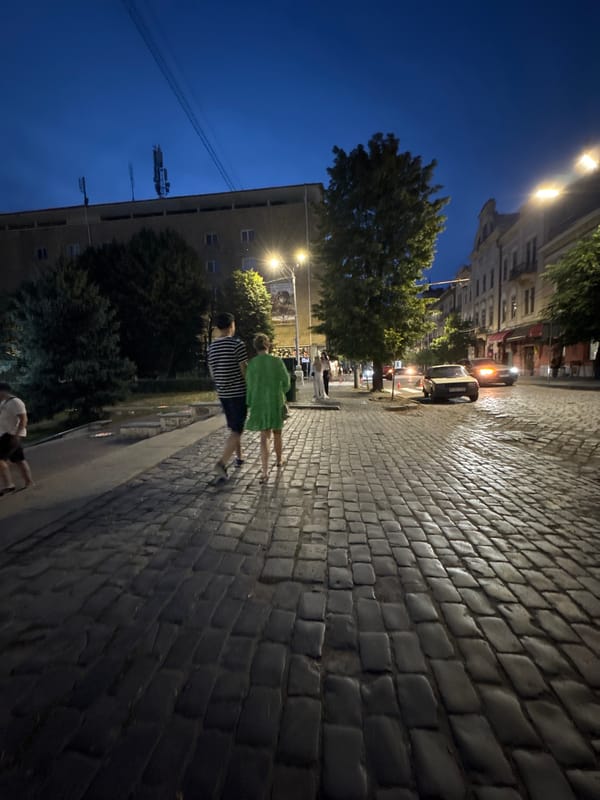 Chernivtsi city center at dusk, landmarks lit and streets active