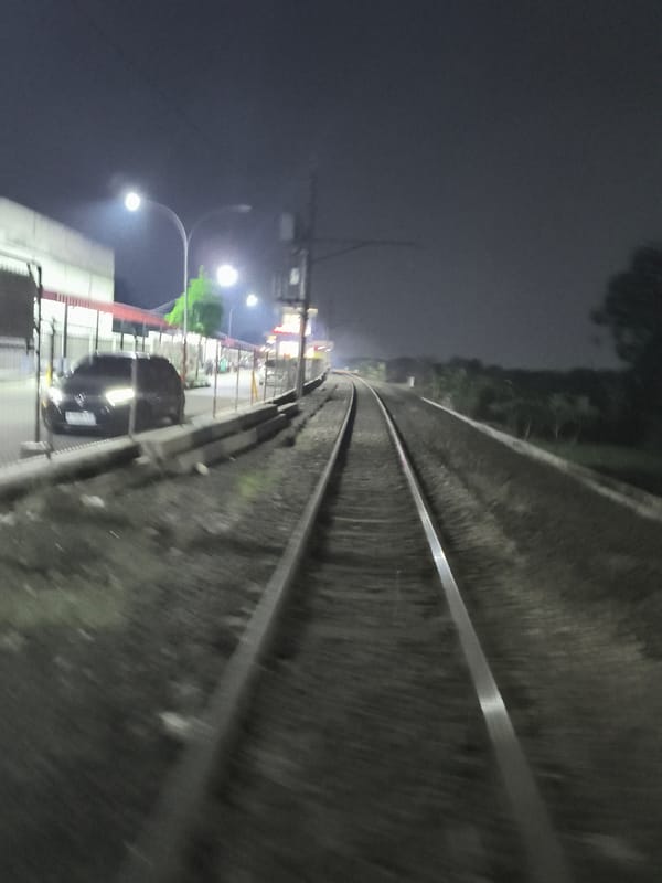 Motion-blurred railway tracks photographed from moving vehicle in Depok