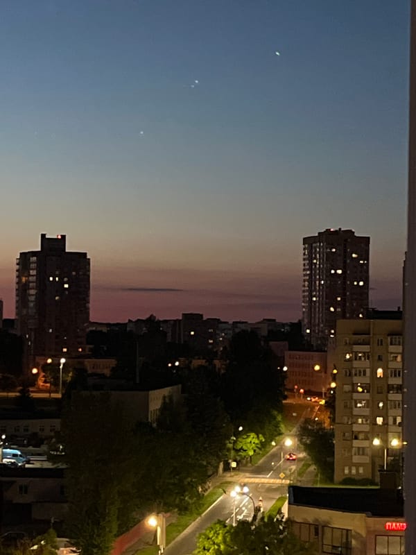 Minsk skyline at dusk, crescent moon rising over apartment blocks