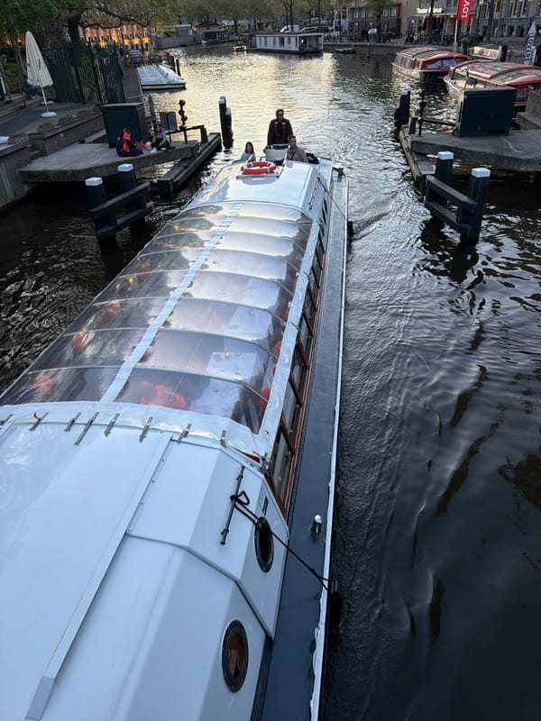 Tourist boat cruises Amsterdam canal at twilight