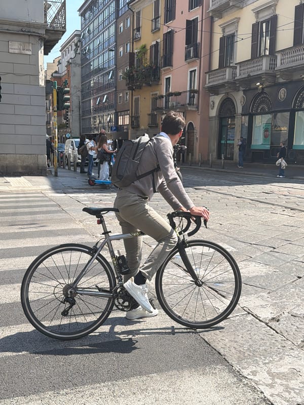 Cyclist spotted on sunlit Milan street amid spring foliage