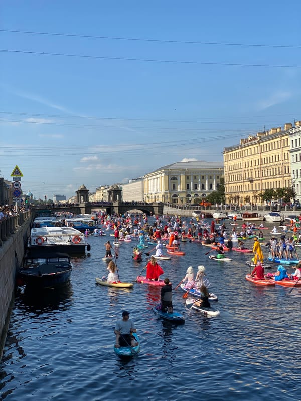 Costumed paddleboarders pack a Saint Petersburg canal during a festival.