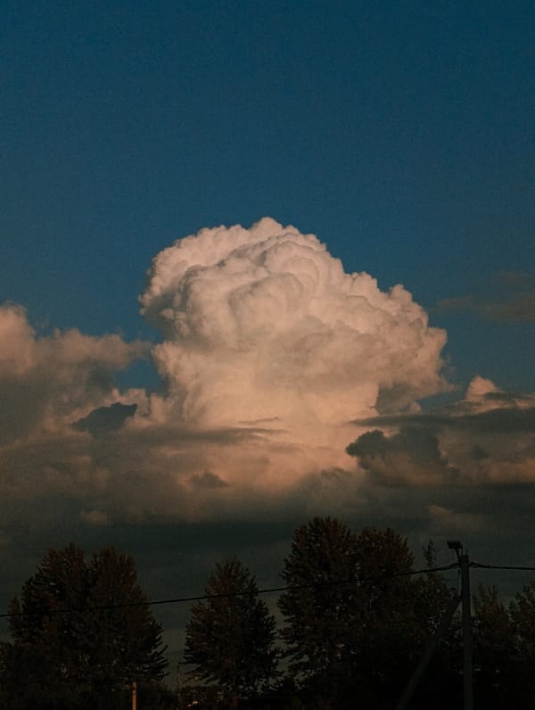 Dramatic cloud formations over rural landscape, golden hour.