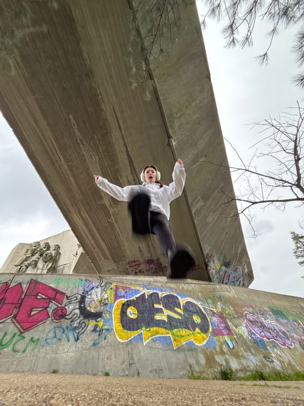 Person performs parkour moves near graffitied concrete structures