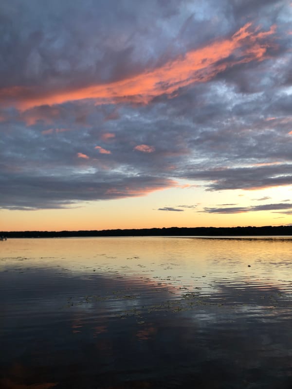 Dramatic sunset over the Svir River, boats and a bike on the bank