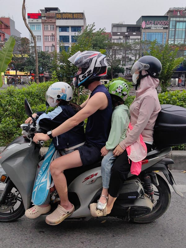 Helmet-wearing family of four shares single scooter in Hanoi