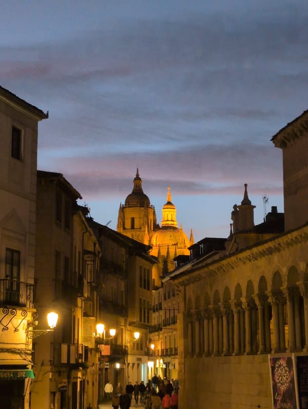 Segovia Cathedral dome illuminated against colorful dusk sky