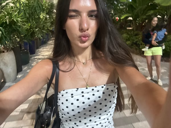 Polka-dot dress selfie session on a paved walkway at night