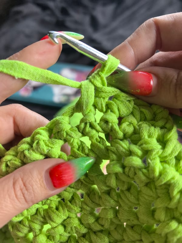 Woman crochets neon green yarn with bulldog companion in Russia