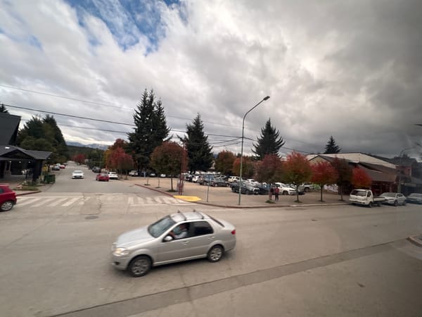 Vehicle crosses intersection in Villa La Angostura under overcast sky