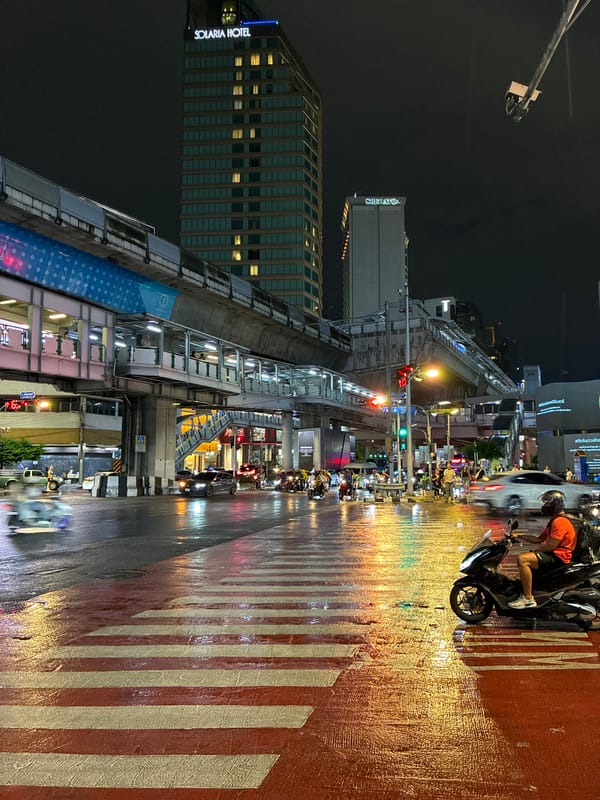 Rainy night reflections at a busy Bangkok intersection