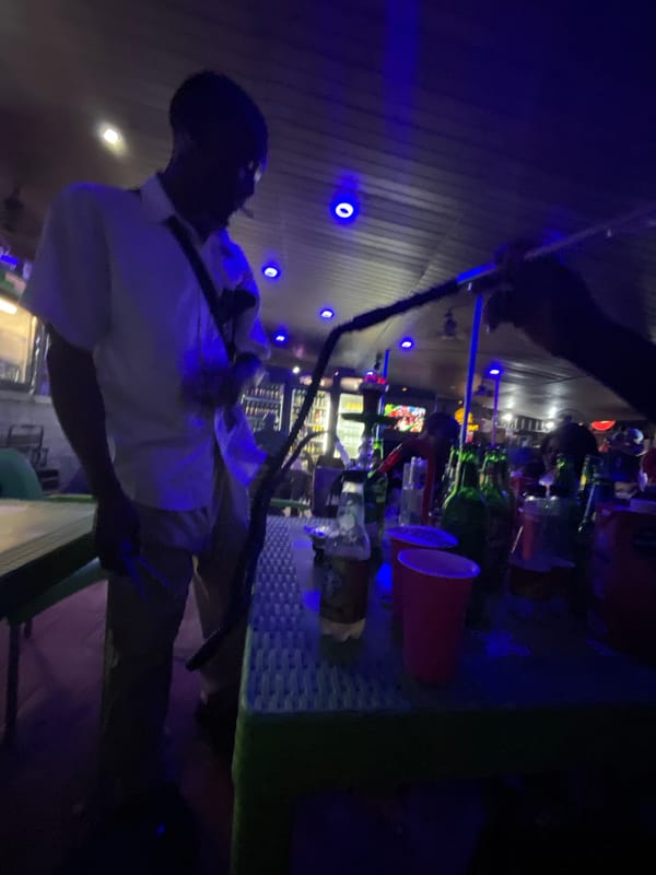 Nigerian youth socialize at blue-lit bars in evening gathering
