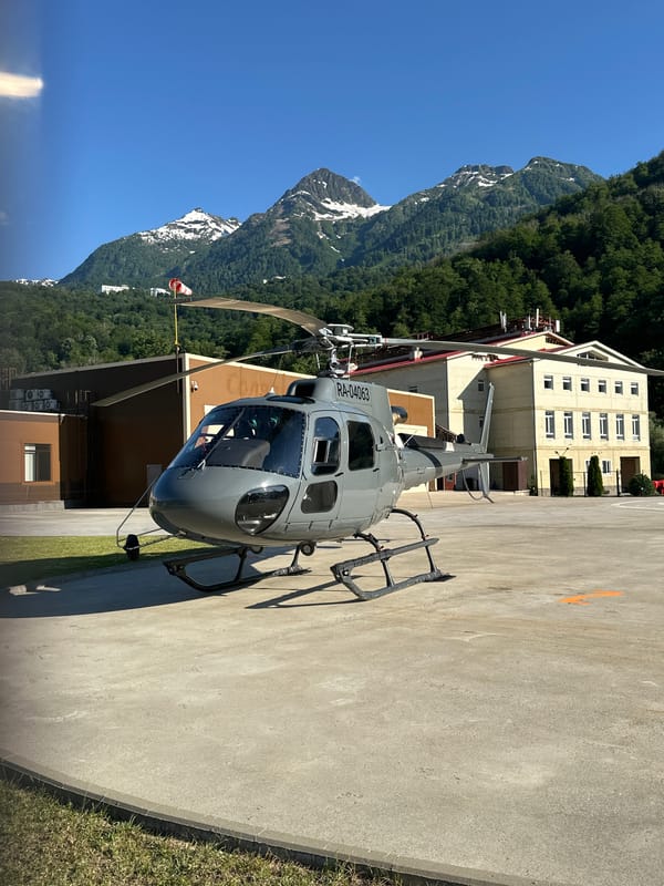 Helicopter parked at Krasnaya Polyana helipad, mountain backdrop