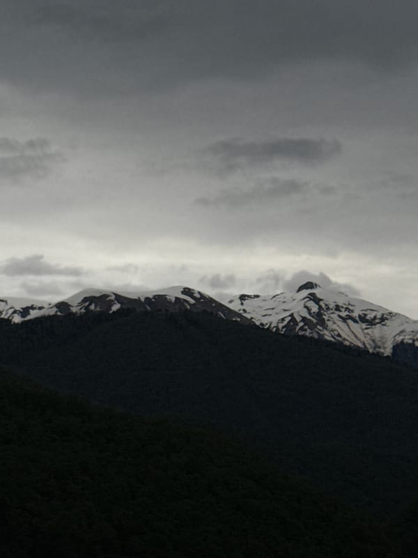 Snow-capped mountains observed under cloudy skies in Krasnaya Polyana