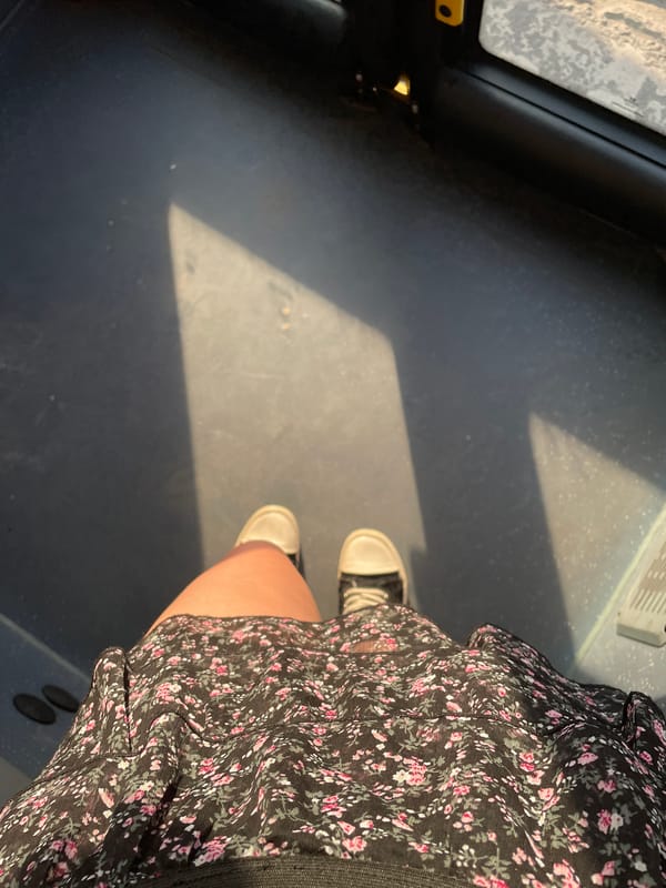 Person in floral dress stands in sunlit indoor space