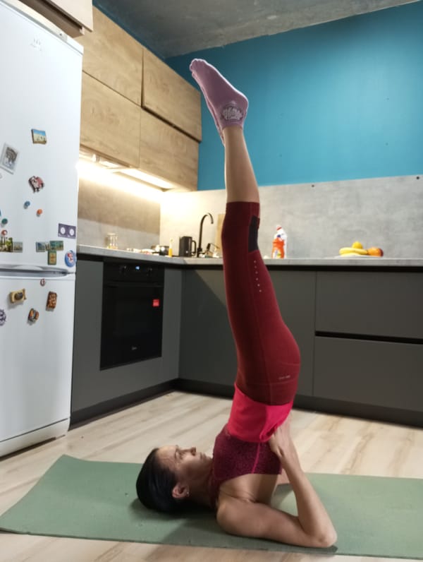 Woman practices morning yoga in kitchen, Pervomaysky Russia